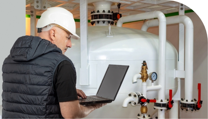 Technician monitoring a wastewater treatment system using a laptop, supporting private utility operations, compliance management, and long-term water infrastructure performance.