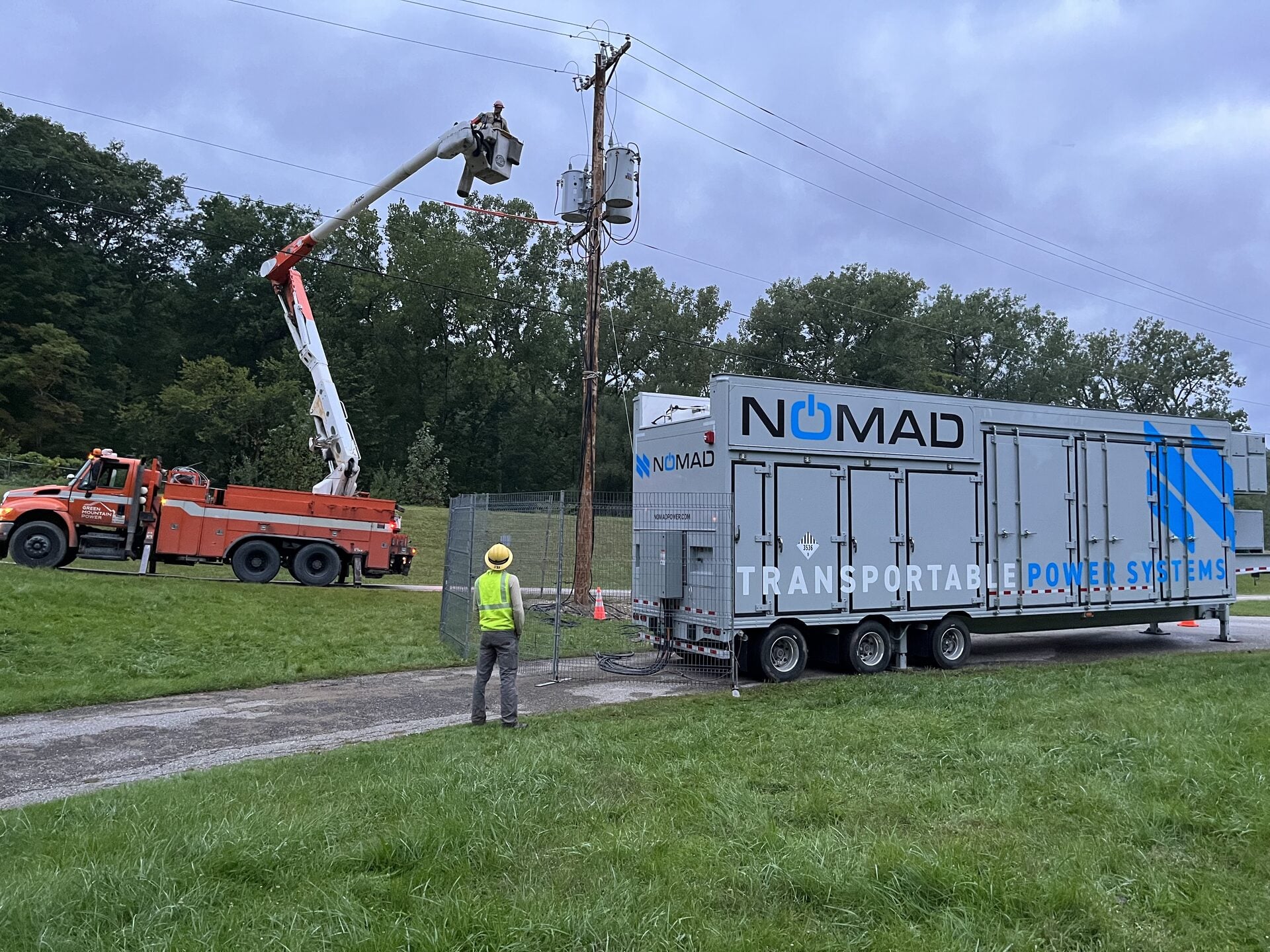 Utility crew working beside a mobile battery energy storage unit.
